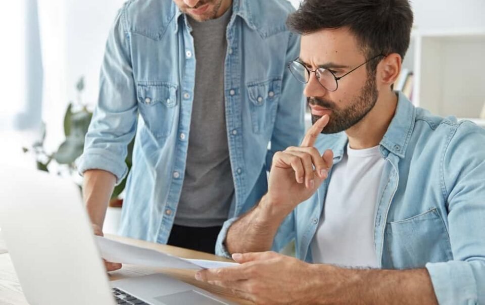 Homem de negócios analisa proposta de compra de imóvel em Cascais com expressão séria.