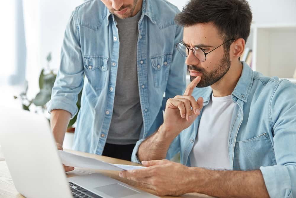Homem olha pensativo para uma proposta de compra de um imóvel.