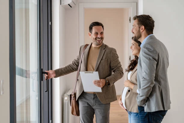 Smiling real estate agent showing a new house to a happy couple ready to buy a home.